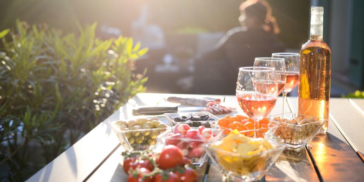 holiday summer brunch party table outdoor in house backyard with appetizer glass of rose wine fresh drink and organic vegetables