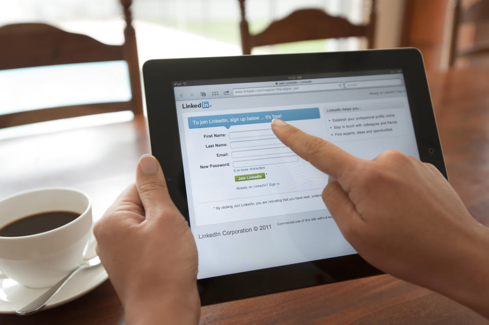 Sydney, Australia - October 28, 2011: Woman holding an ipad showing the Linkedin login screen. Close-up shot of her hands and the iPad screen. She is touching the screen. This shot shows the ipad being used in a casual environment.