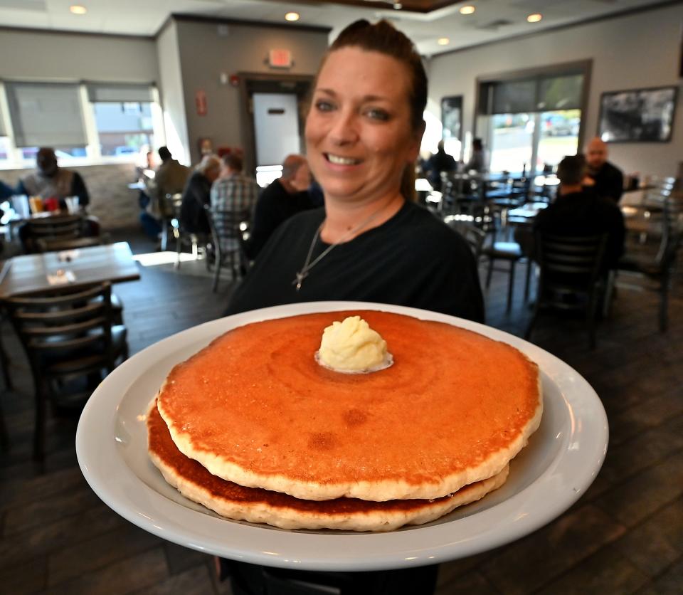 City Line Diner server Jamie Evans carries a plate of giant buttermilk pancakes.