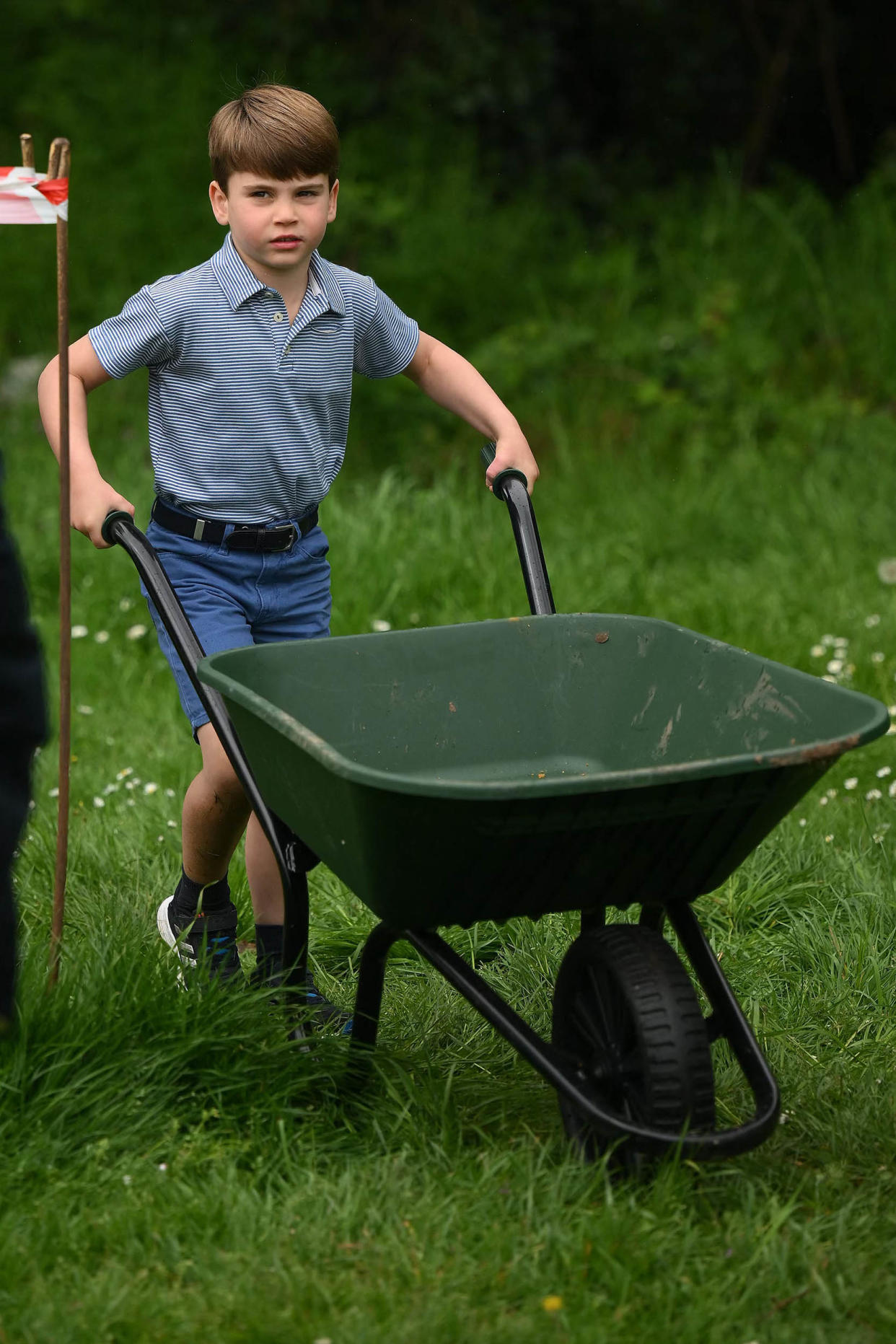Prince Louis of Wales takes control of a wheelbarrow as he helps his parents take part in the Big Help Out, during a visit to the 3rd Upton Scouts Hut in Slough, west of London on May 8, 2023, where they joined volunteers helping to renovate and improve the building.  (Daniel Leal / AFP via Getty Images)