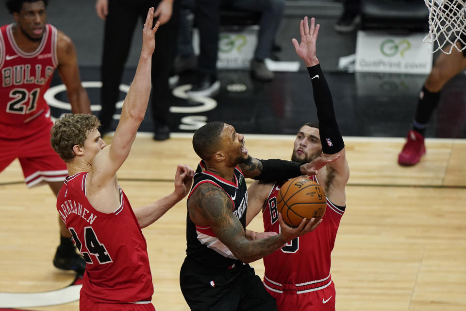 Portland Trail Blazers guard Damian Lillard, center, drives to the basket against Chicago Bulls forward Lauri Markkanen, left, and guard Zach LaVine during the second half of an NBA basketball game in Chicago, Saturday, Jan. 30, 2021. (AP Photo/Nam Y. Huh)