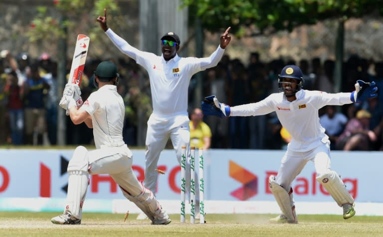 Sri Lanka's captain Angelo Mathews (C) and wicketkeeper Dinesh Chandimal (R) celebrate the wicket of Australia's Adam Voges on the third day of the second Test at the Galle International Cricket Stadium, on August 6, 2016