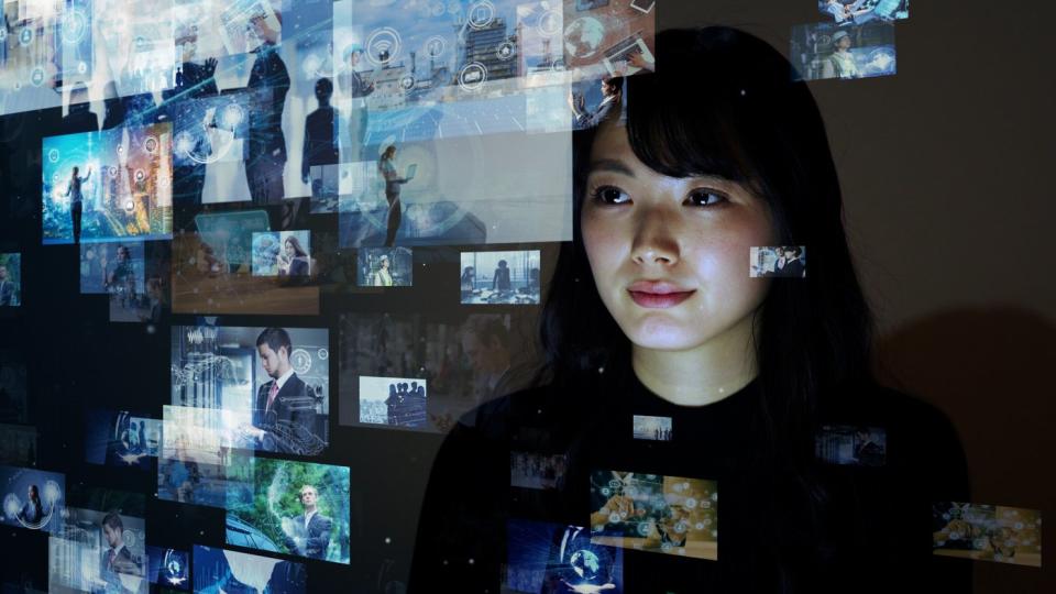 A woman looking at images on a transparent screen.