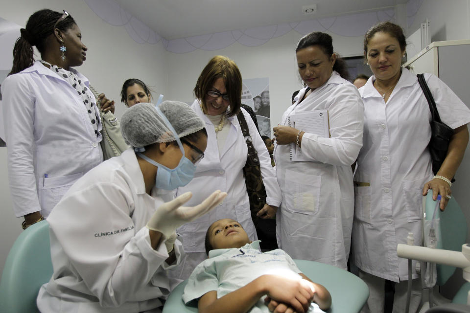 FILE - In this Aug. 30, 2013 file photo, Cuban doctors observe a dental procedure during a a training session at a health clinic in Brasilia, Brazil. Cuba said Wednesday, Nov. 14, 2018, it is ending a program that sent government doctors to remote regions of Brazil in exchange for millions in badly needed dollars. The end of the "Mas Medicos," or "More Doctors," program signals a sharp deterioration in relations between communist Cuba and Brazil, which just elected far-right presidential candidate Jair Bolsonaro. (AP Photo/Eraldo Peres, File)