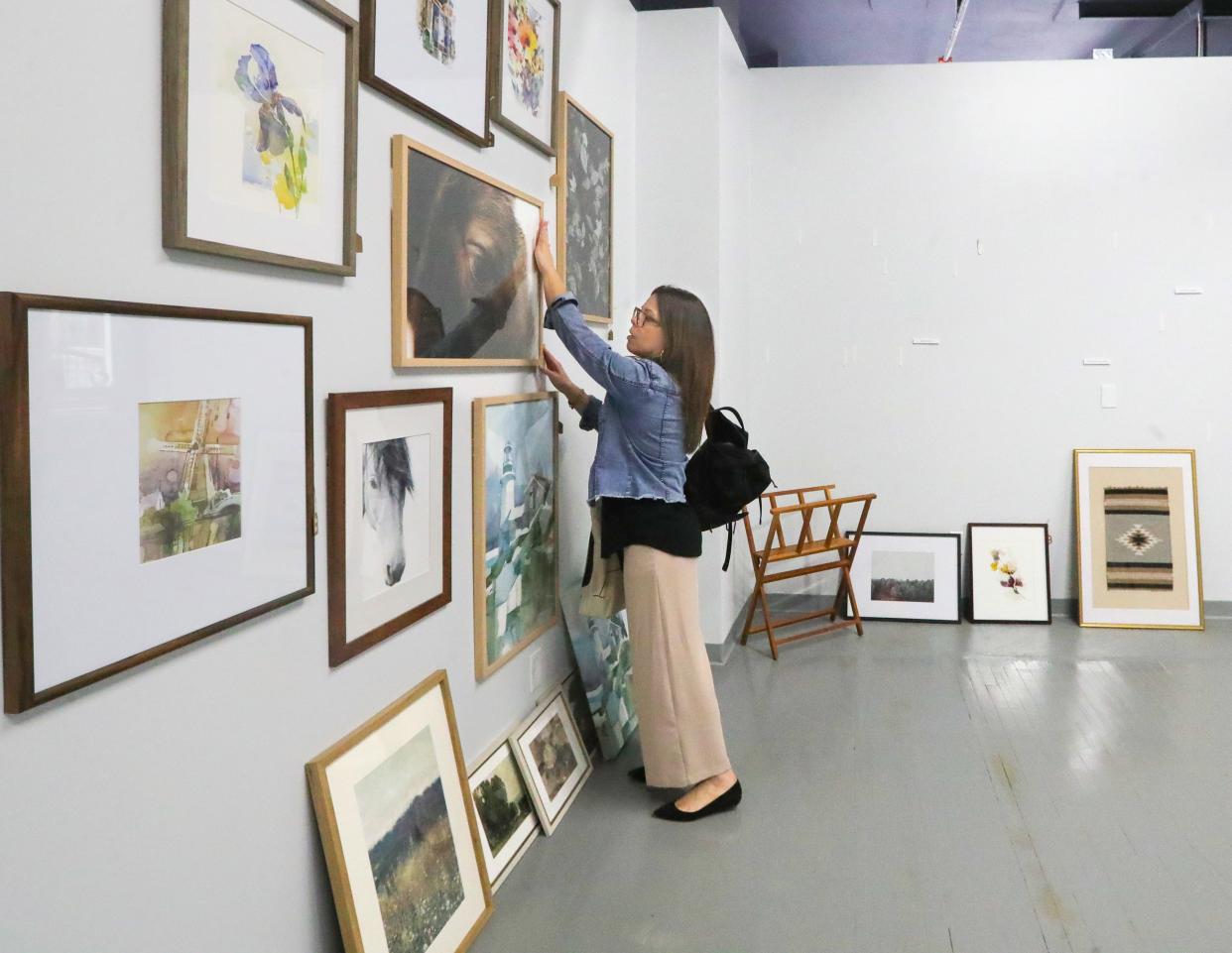 Artist Robin Ott straightens a photo on the wall of the Hue Design Company located on the ground floor at 159 S. Main Street.