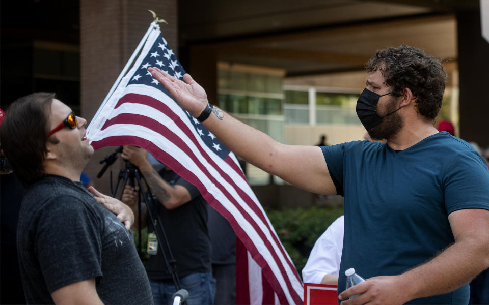 A man gestures, left, after a counterprotester crossed the street to make his case, during a rally held by Republican Reps. Marjorie Taylor Greene and Matt Gaetz near City Hall in Riverside, Calif., Saturday, July, 17, 2021. (Cindy Yamanaka/The Orange County Register via AP)