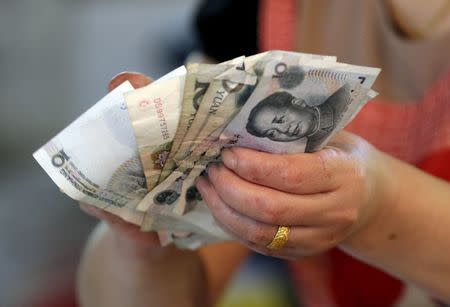 A vendor holds Chinese Yuan notes at a market in Beijing, in this August 12, 2015 file photo. REUTERS/Jason Lee/Files