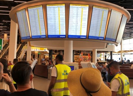 People and staff wait at Amsterdam Schiphol airport