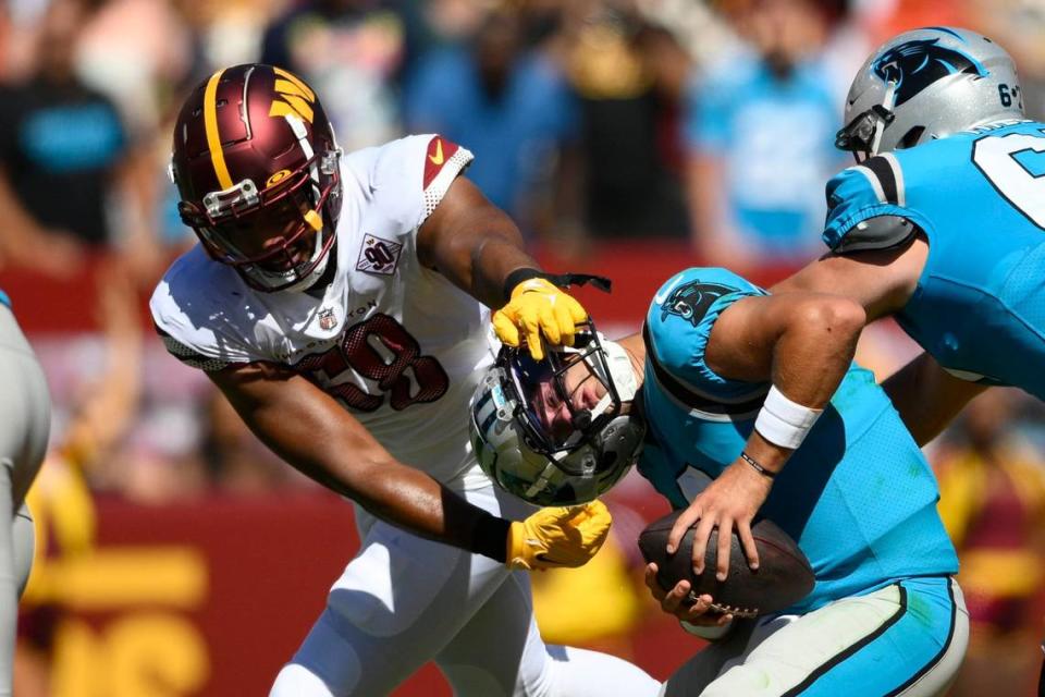 Washington Commanders defensive end Shaka Toney, left, grabs the face mask of Carolina Panthers quarterback Matt Corral, center, during the second half of a preseason NFL football game, Saturday, Aug. 13, 2022, in Landover, Md. The Panthers won 23-21.