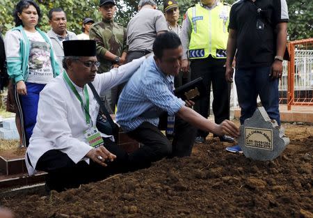 An Islamic cleric (L) consoles a relative of Indonesian death row prisoner Zaenal Abidin during his funeral in Cilacap, Central Java, Indonesia, April 29, 2015. REUTERS/Beawiharta