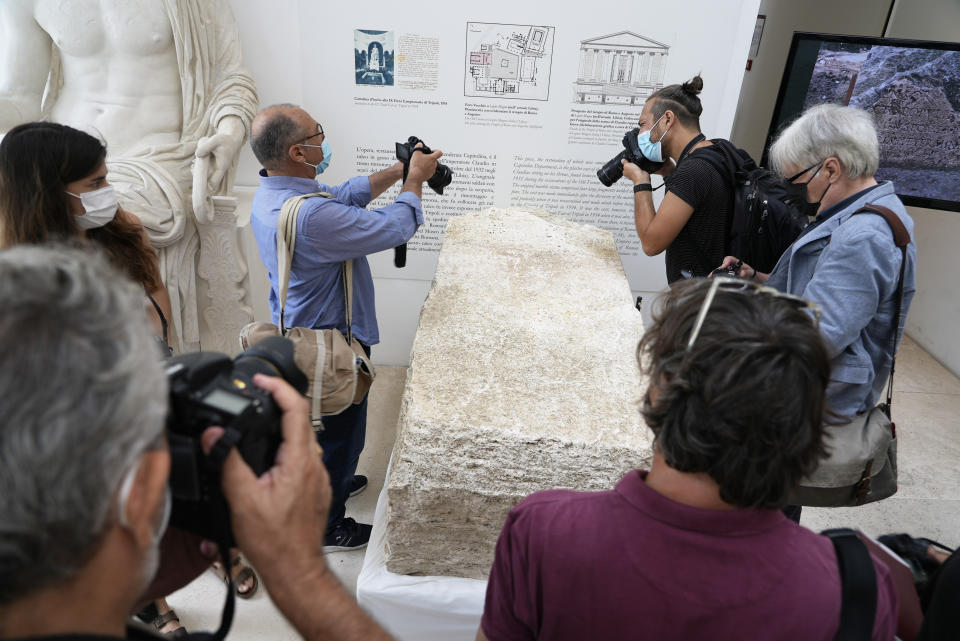 Photographers take pictures during the presentation to the press of an archeological finding emerged during the excavations at a Mausoleum in Rome, Friday, July 16, 2021. The monumental pomerial stone is dating back to Roman Emperor Claudio and was used to mark the ‘pomerium’ the sacred boundaries of the ‘Urbe’, the city of Rome, during the Roman empire. (AP Photo/Domenico Stinellis)