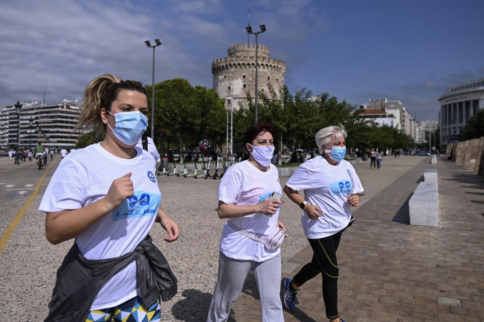 People participate in an event, organized by the local medical association, to support the use of protective masks, in the northern city of Thessaloniki, Greece, Saturday, Oct. 3, 2020. Lung doctors staged a public demonstration of the benefits of face masks by fast-walking a distance of 2 kilometers (1.25 miles) through the city center aiming to debunk a widely-circulated rumor by anti-mask conspiracy theorists that wearing one left people short of breath. (AP Photo/Giannis Papanikos)