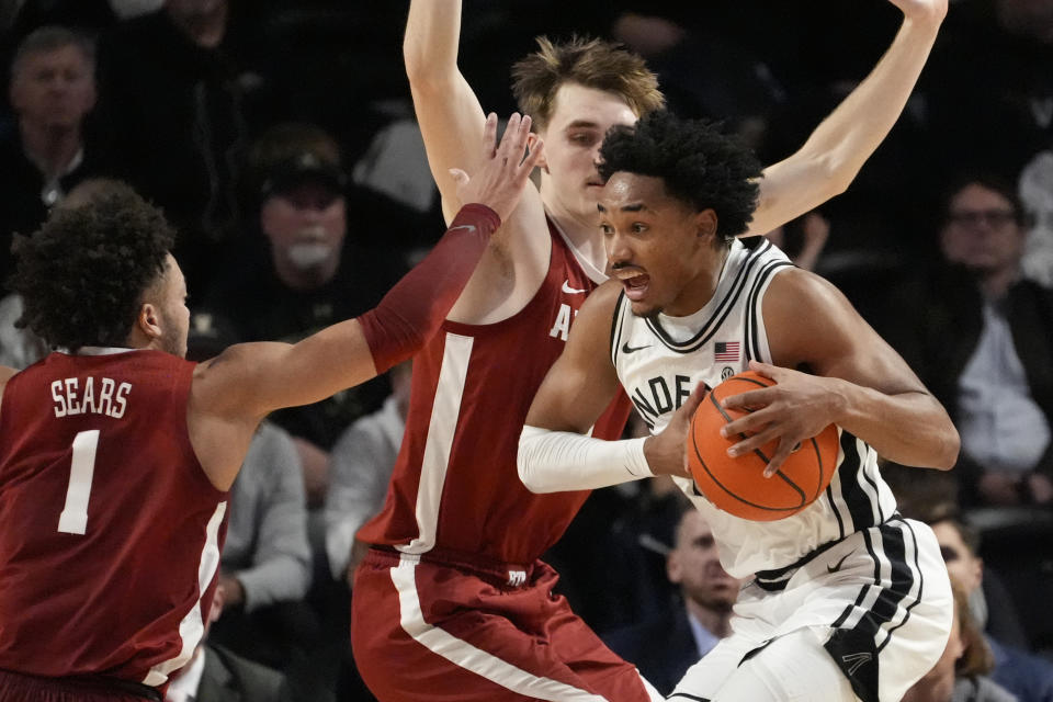 Vanderbilt guard Tyrin Lawrence, right, drives to the basket past Alabama guard Mark Sears (1) and forward Grant Nelson, center, during the second half of an NCAA college basketball game Saturday, Jan. 6, 2024 in Nashville, Tenn. Alabama won 78-75. (AP Photo/George Walker IV)