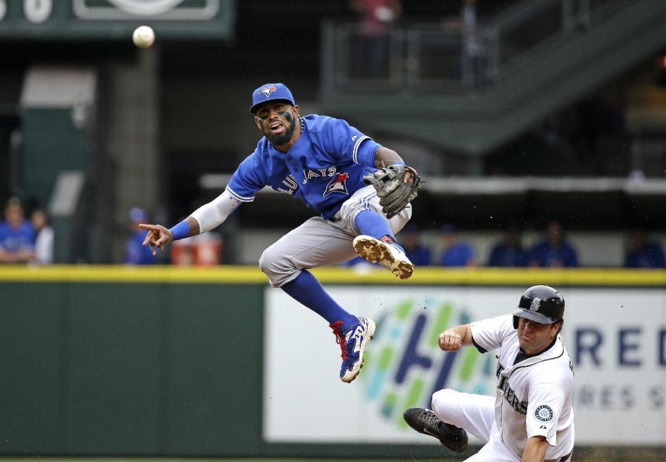 Toronto Blue Jays shortstop Jose Reyes, left, leaps out of the way after forcing out Seattle Mariners' Seth Smith at second base and throwing to first in the third inning of a baseball game Saturday, July 25, 2015, in Seattle. Logan Morrison was safe at first on the fielder's choice. (AP Photo/Elaine Thompson)