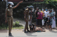 A family member of an inmate pleads lying at the feet of a policeman demanding to know the condition of her relative outside the Mahara prison complex following an overnight unrest in Mahara, outskirts of Colombo, Sri Lanka, Monday, Nov. 30, 2020. Sri Lankan officials say six inmates were killed and 35 others were injured when guards opened fire to control a riot at a prison on the outskirts of the capital. Two guards were critically injured. Pandemic-related unrest has been growing in Sri Lanka's overcrowded prisons. (AP Photo/Eranga Jayawardena)