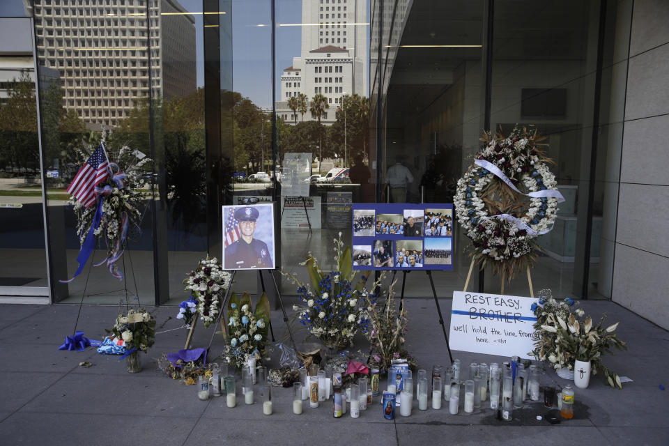 A memorial for slain police officer Juan Diaz is placed outside of Los Angeles Police Department headquarters Tuesday, Aug. 6, 2019, in Los Angeles. Authorities say the fatal shooting of the off-duty Los Angeles police officer occurred during a two-hour series of crimes by gang members that included another attempted shooting where the targets were unhurt. Prosecutors on Tuesday filed multiple charges against the three suspects arrested last week in the killing of Officer Diaz. (AP Photo/Marcio Jose Sanchez)