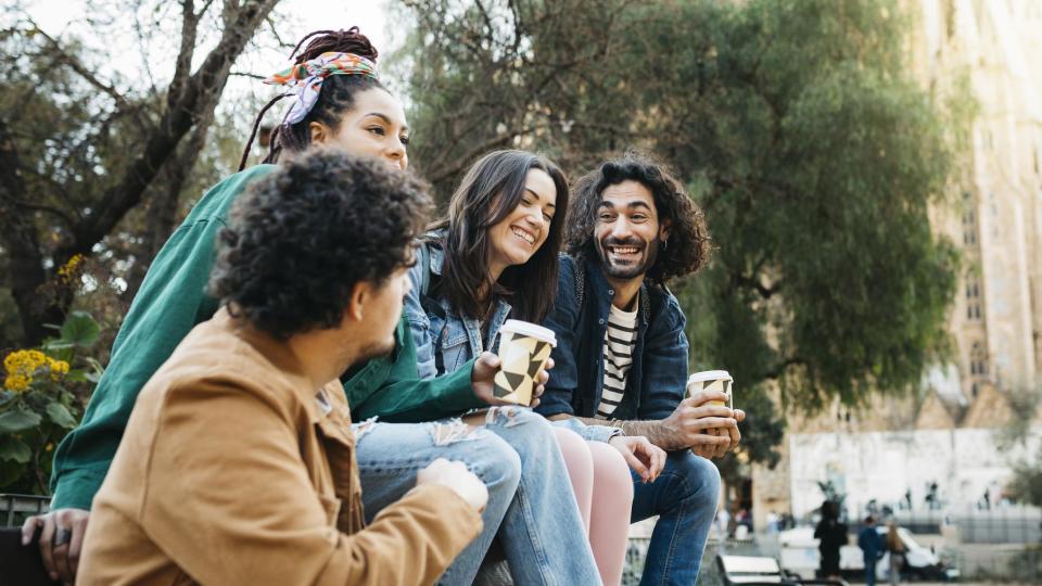 grupo de jóvenes comparten un café en una plaza