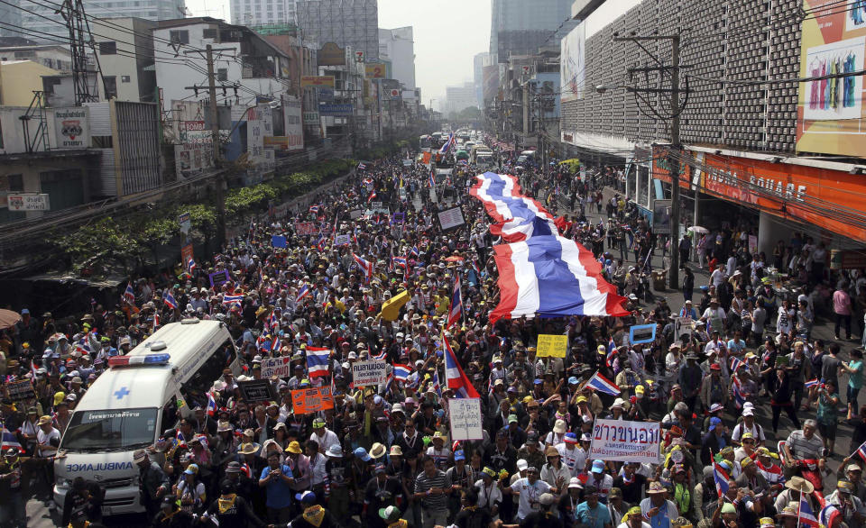 Thai anti-government protesters take to a street with a giant national flag during a march in Bangkok, Thailand Saturday, Jan. 25, 2014. Thailand's ruling party has questioned the reasoning behind a court decision allowing next month's general election to be postponed, but held open the possibility that it might agree to put off the polls if its political rivals agree to recognize the legitimacy of a new vote. (AP Photo/Apichart Weerawong)