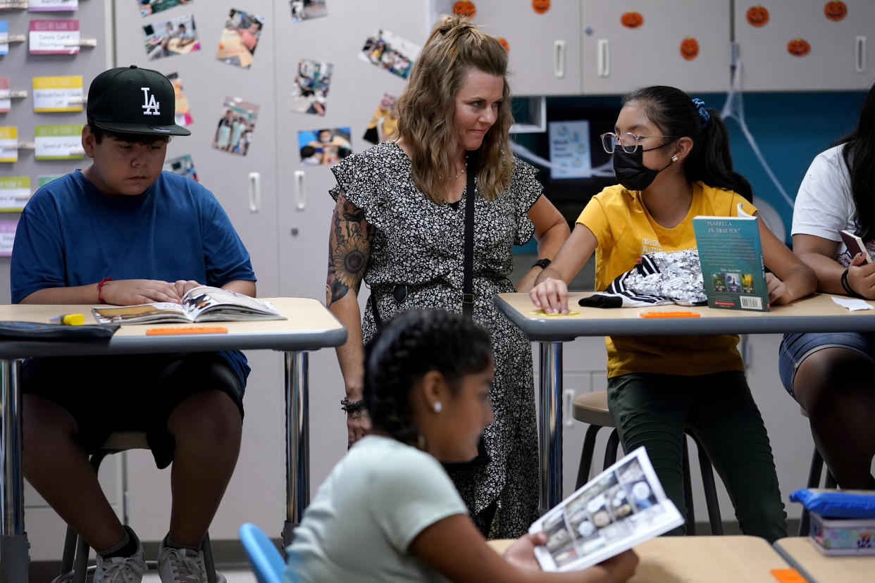 Whittier Elementary School principal Andrea Lang Sims interacts with a student, Tuesday, Oct. 18, 2022 in Mesa, Ariz. Like many school districts across the country, Mesa has a teacher shortage due in part due to low morale and declining interest in the profession. Five years ago, Mesa allowed Whittier to participate in a program making it easier for the district to fill staffing gaps, grant educators greater agency over their work and make teaching a more attractive career. The model, known as team teaching, allows teachers to combine classes and grades rotating between big group instruction, one-on-one interventions, small study groups or whatever the team agrees is a priority each day. (AP Photo/Matt York)
