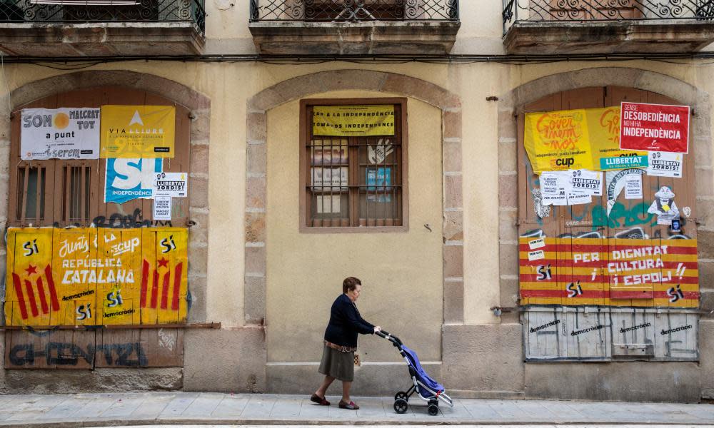 A woman walks past Catalan pro-independence graffiti in Barcelona, Spain