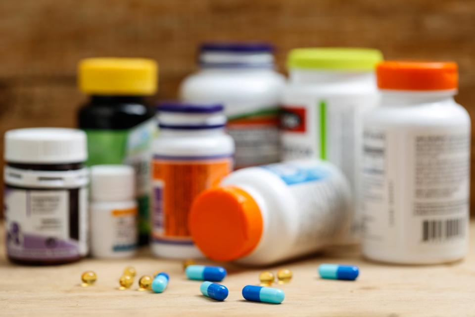 Bottles of medicine and vitamins on countertop with blue prescription pills on counter