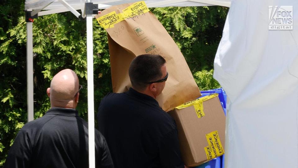 Police carry evidence outside of a suburban home