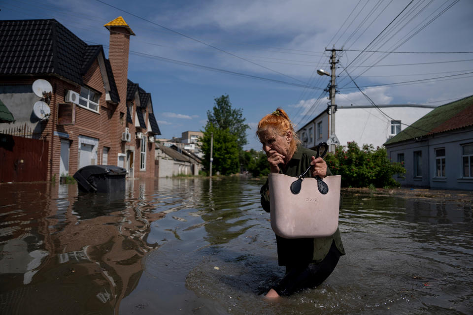 A local resident makes her way through a flooded road after the walls of the Kakhovka dam collapsed overnight, in Kherson, Ukraine, on Jun 6.<span class="copyright">Evgeniy Maloletka—AP</span>