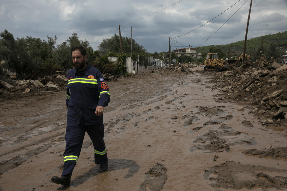 A Civil Protection staff walks on a destroyed street following a storm, at the village of Politika, on Evia island, northeast of Athens, on Sunday, Aug. 9, 2020. An elderly couple and an 8-month-old baby have been found dead and dozens have been trapped in their homes and cars from a storm that has hit the island of Evia, in central Greece, police say. (AP Photo/Yorgos Karahalis)