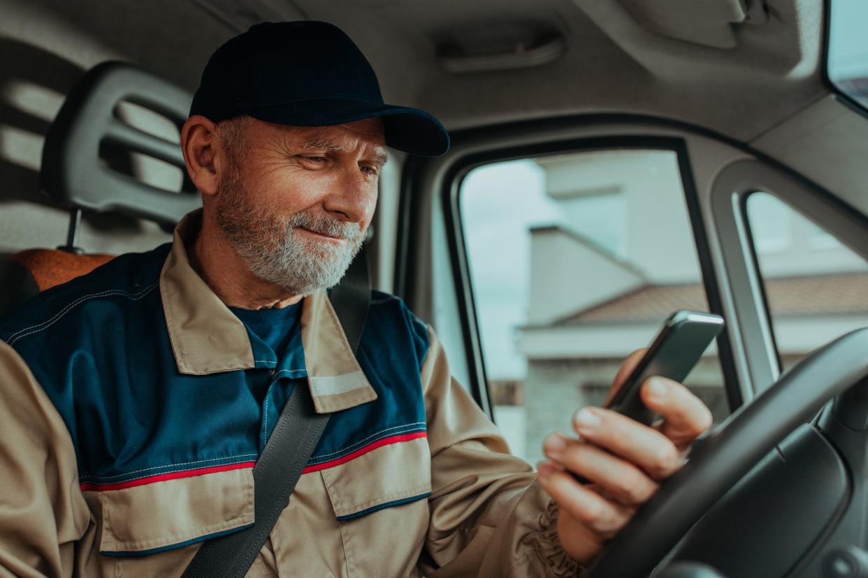 Delivery man checking number of costumer on his phone