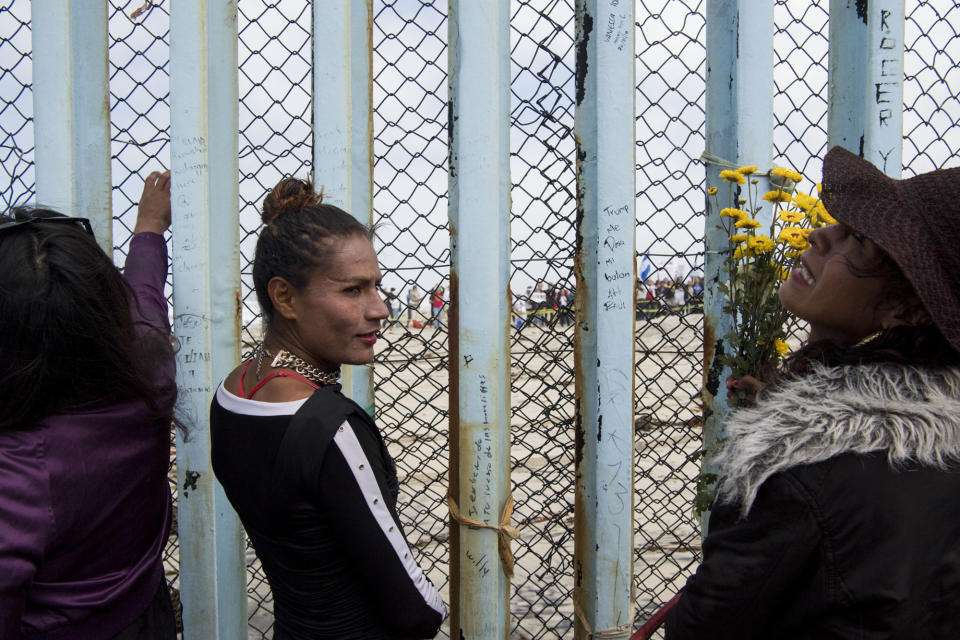 People stand along the border wall to look at the march on the U.S. side of the border at Friendship Park.