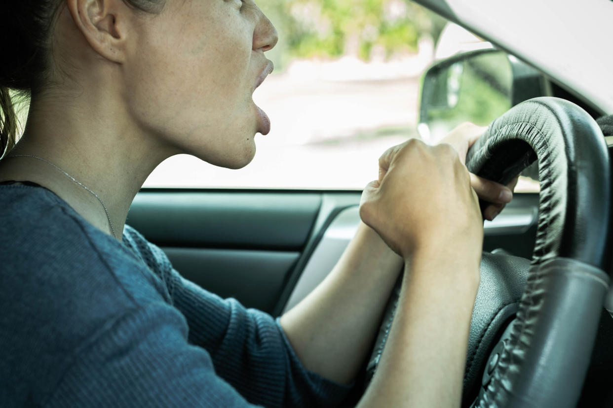 Road rage. Angry woman driving her car honking the horn and yelling.