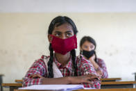 Students wear masks and sit following social distancing measures as a precautionary measure against the coronavirus, as they attend a class at the Government Senior Secondary School in Dari, near Dharmsala, India, Friday, Nov. 6, 2020. (AP Photo/Ashwini Bhatia)