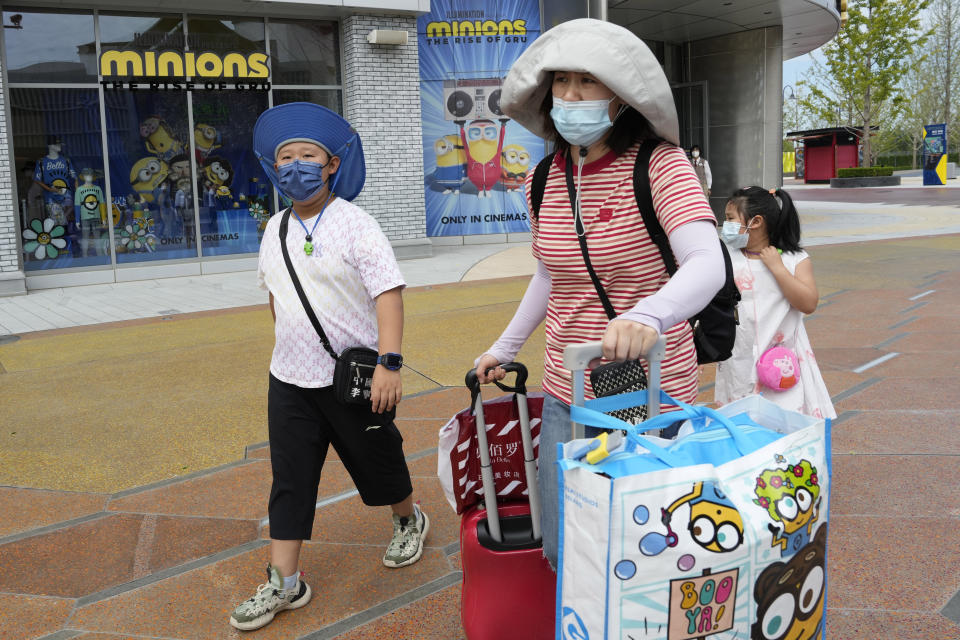 Visitors outside the Universal Studio Beijing theme park pass by a shop selling memorabilia for the latest "Minions: The Rise of Gru" movie in Beijing, Wednesday, Aug. 24, 2022. The latest “Minions” movie reinforces a message for Chinese audiences that viewers in other countries won’t see: Crime doesn’t pay. (AP Photo/Ng Han Guan)