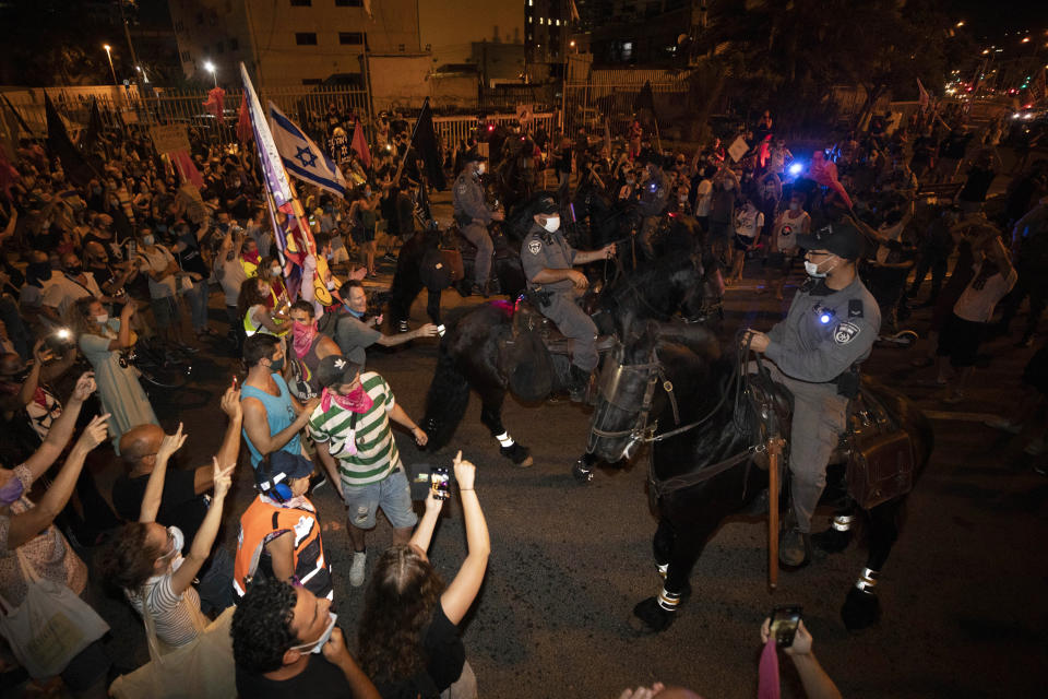 Israeli police officers on horseback block Israeli protesters during a demonstration against lockdown measures that they believe are aimed at curbing protests against Prime Minister Benjamin Netanyahu, in Tel Aviv, Israel, Thursday, Oct. 1, 2020. (AP Photo/Sebastian Scheiner)