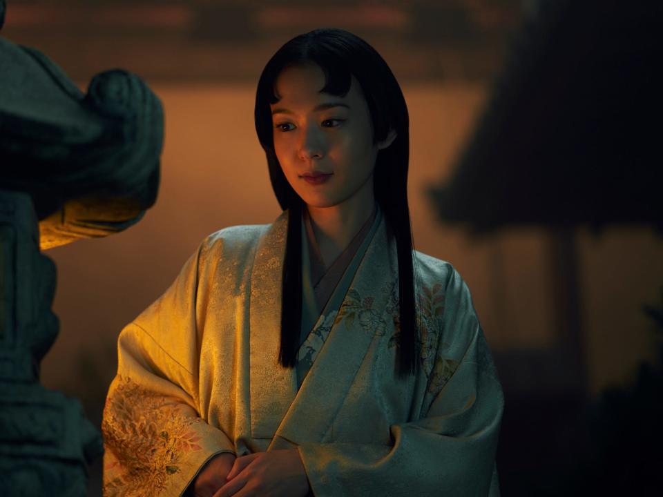 moeka hoshi as usami fuji, a young woman with short cut bangs, long straight hair, and golden robes