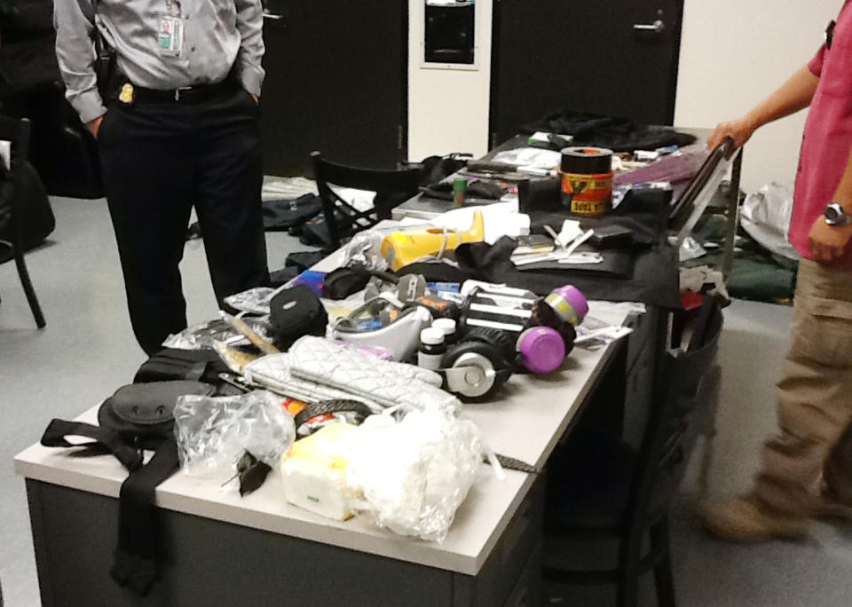 This image provided by the Los Angeles Police Department shows officials seizing material from the luggage of Yongda Huang Harris after he atempted to enter the United States at Los Angeles International Airport. A detention hearing was held Friday Oct. 12, 2012 for Harris where he was remanded back into custody. (AP Photo/LAPD)