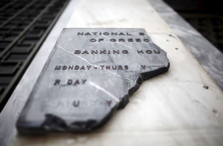 A damaged sign of National Bank of Greece, is seen at the entrance of the bank's head office in Athens, April 24, 2015. REUTERS/Kostas Tsironis