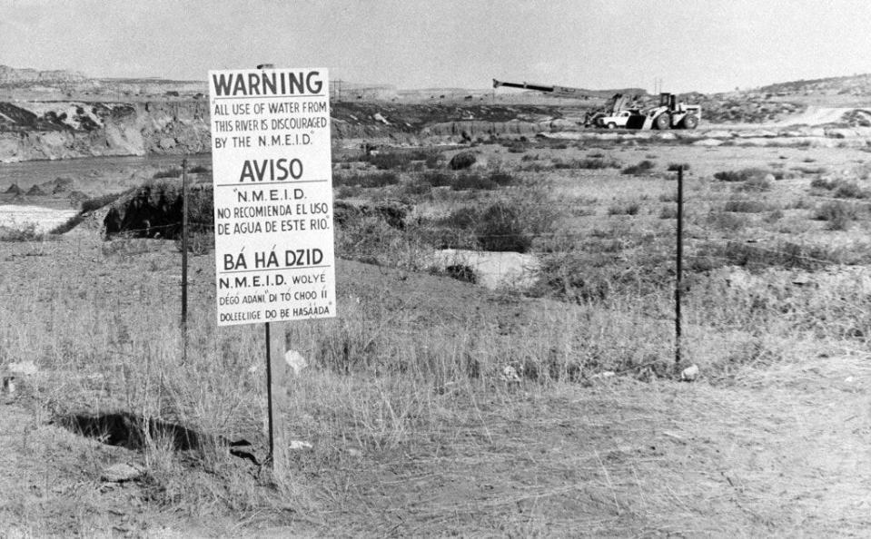 FILE - In this Nov. 13, 1979, file photo, while United Nuclear Corp. uses a combination of hand work and heavy machinery to clear up a uranium tailings spill along the Rio Puerco, signs warn residents in three languages to avoid the water in Church Rock, N.M. A bipartisan group of lawmakers is renewing the push to expand a federal compensation program for radiation exposure following uranium mining and nuclear testing carried out during the Cold War. Advocates have been trying for years to bring awareness to the lingering effects of nuclear fallout surrounding the Trinity Site in southern New Mexico and on the Navajo Nation, where more than 30 million tons of ore were extracted over decades to support U.S. nuclear activities. (AP Photo/SMH, File)