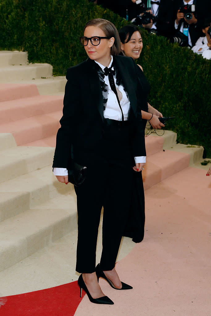 Lena in formal tuxedo with bow tie standing on stairs, photographers in background