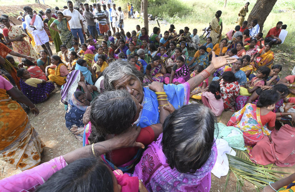 Indian women mourn the death of relatives in a case of suspected food poisoning at Bidarahalli, near Sulawadi village in Chamarajnagar district of Karnataka state, India, Saturday, Dec. 15, 2018. Police on Saturday arrested three people after at least 10 died of suspected food poisoning following a ceremony to celebrate the construction of a new Hindu temple in southern India. (AP Photo/Madhusudhan Sr)