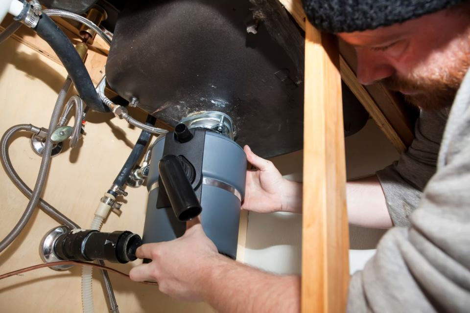 Man attaching garbage disposal to the mounting ring.