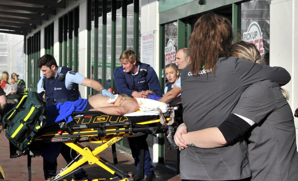 Supermarket staff embrace as police officers take a victim to an ambulance outside a Countdown supermarket in central Dunedin, New Zealand, Monday May 10, 2021. A man began stabbing people at a New Zealand supermarket Monday, wounding five people, three of them critically, according to authorities. (Christine O'Connor/Otago Daily Times via AP)