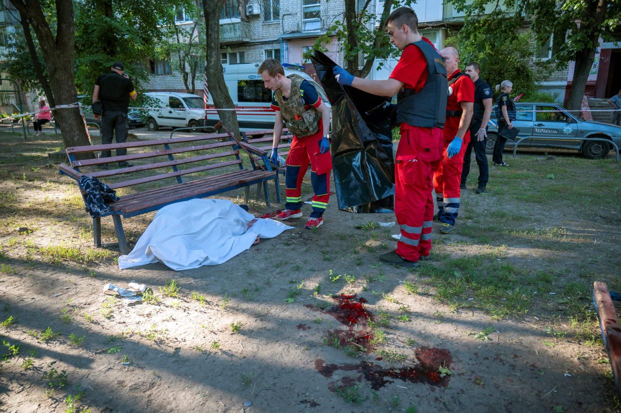 Rescuers cover the body of an elderly man who was killed in a rocket attack on a residential area in Kharkiv on June 27, 2022. 