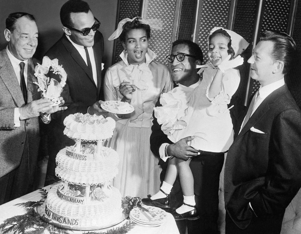 <p>The Rat Pack member and his bride are surrounded by fellow stars comic Joe E. Lewis (left), singer Harry Belafonte (second from left), and actor Donald O'Connor, who served as best man. After their ceremony at the Sands Hotel, they were snapped cutting into their cake. </p>