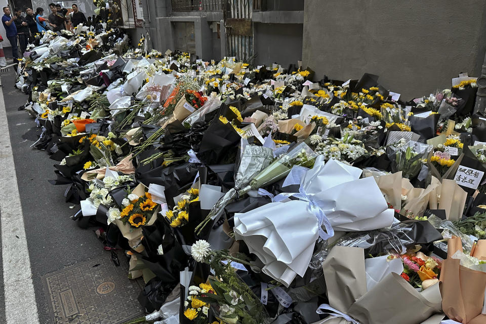 Residents look at the flowers placed outside a residential building where the late Chinese Premier Li Keqiang spent his childhood in Hefei city, in central China's Anhui province, Saturday, Oct. 28, 2023. The sudden death of China's former second-ranking leader, Li Keqiang, has shocked many people in the country, with tributes offered up to the ex-official who promised market-oriented reforms but was politically sidelined. (Chinatopix via AP)