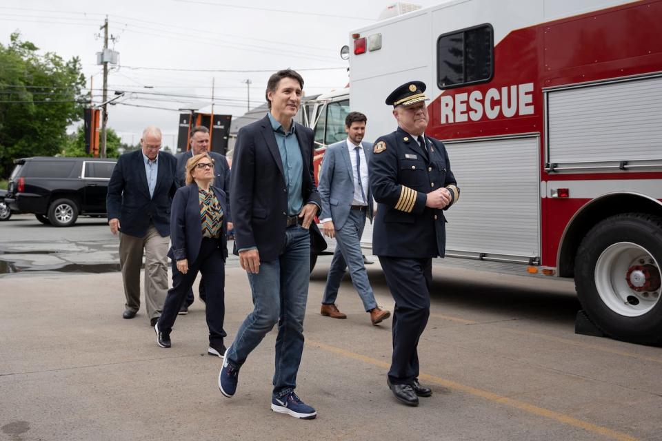 Prime Minister Justin Trudeau, centre, walks with Halifax Regional Fire and Emergency Chief Ken Stuebing, right, while visiting Fire Station 50 in Hammonds Plains, N.S. before meeting with firefighters who battled the wildfires in Nova Scotia.