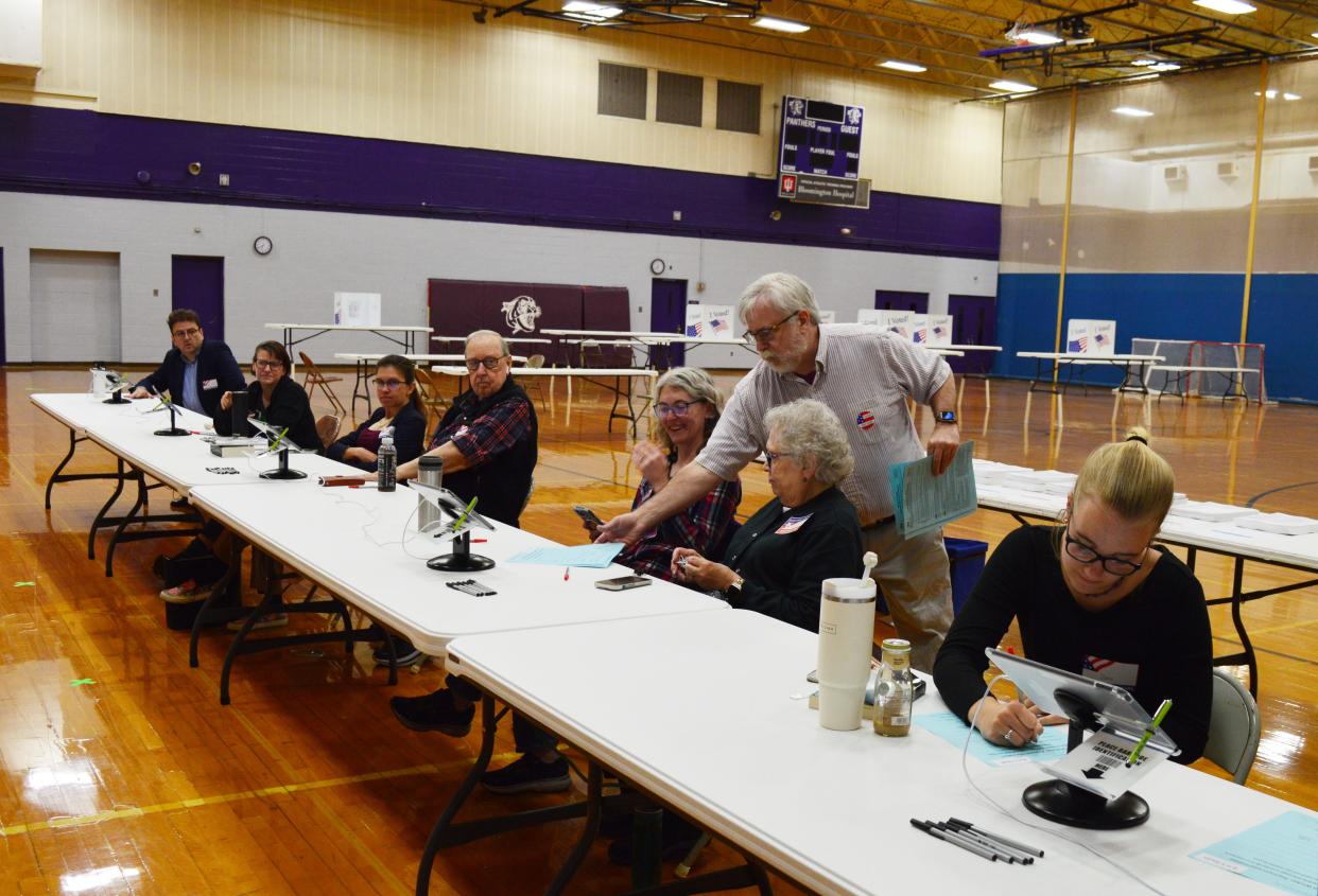 Kurt Seiffert, center, hands out forms to poll clerks working at Bloomington High School South for the May 7, 2024, primary election.