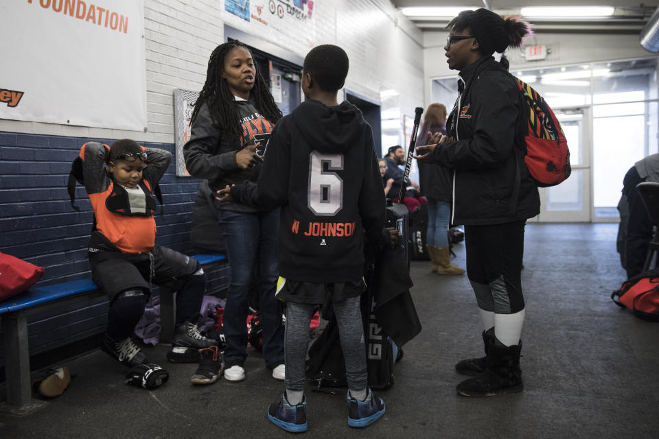 In this Feb. 21, 2019 photo April Johnson, center left, speaks with children Malakye, center, and Wylla as her other son Logan, left, puts on his pads for Snider Hockey practice at the Scanlon Ice Rink in Philadelphia. (AP Photo/Matt Rourke)