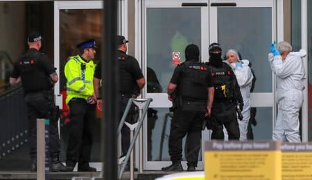 Police forensic officers stand with armed officers outside the Arndale shopping centre after several people were stabbed in Manchester, Britain