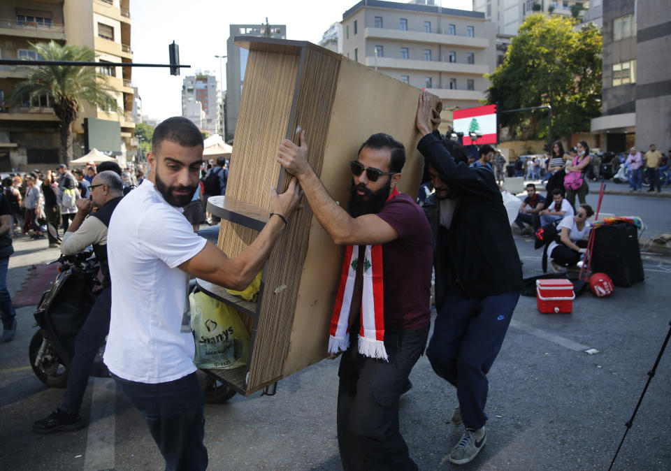 Anti-government protesters remove their belongings as they open a main highway they closed for more then ten days during protests, in Beirut, Lebanon, Wednesday, Oct. 30, 2019. Lebanese banks have been closed for the last two weeks as the government grapples with mass demonstrations that have paralyzed the country, but an even greater crisis may set in when they reopen Friday. (AP Photo/Hussein Malla)